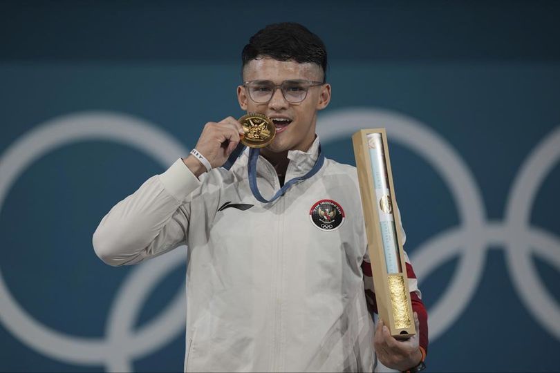 Atlet angkat besi putra Indonesia, Rizki Juniansyah, mempersembahkan medali emas yang ia raih di kelas 73 kg putra Olimpiade Paris 2024